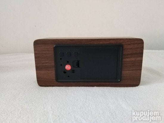 Drveni digitalni sat uz koji je priložen DC adapter.
